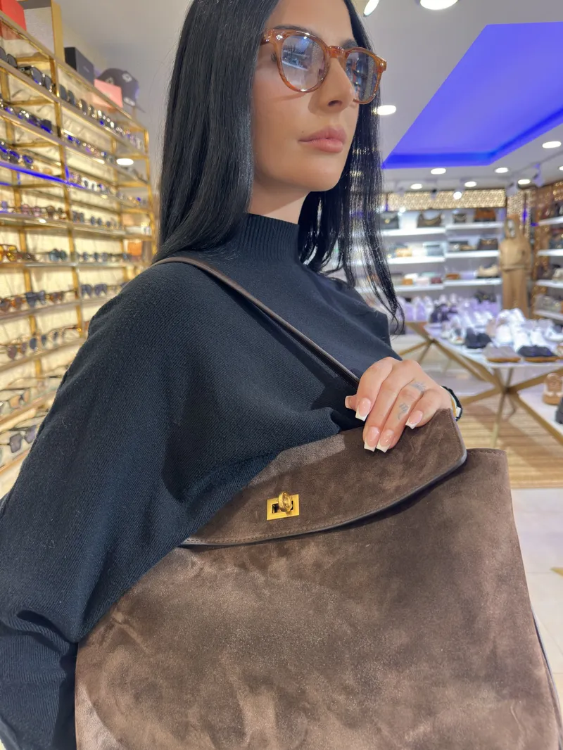 Close-up of a brown suede handbag carried on the shoulder