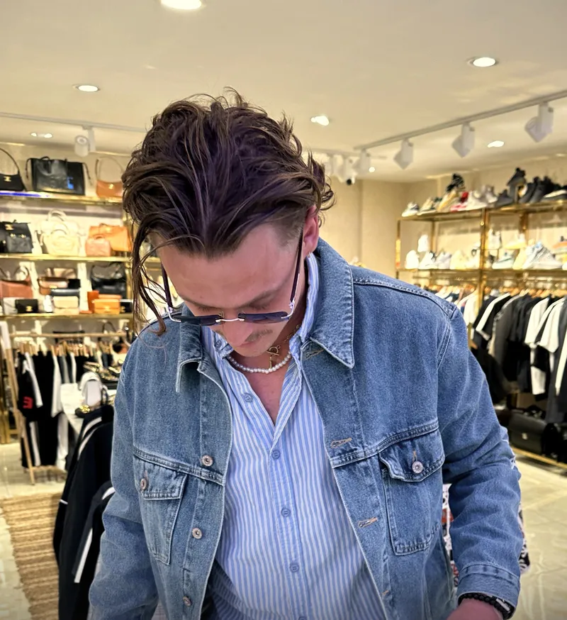 A guest trying on a denim jacket over a striped shirt in the store
