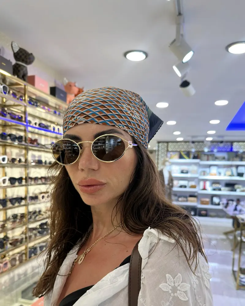A visitor in a bandana and sunglasses by the sunglasses wall