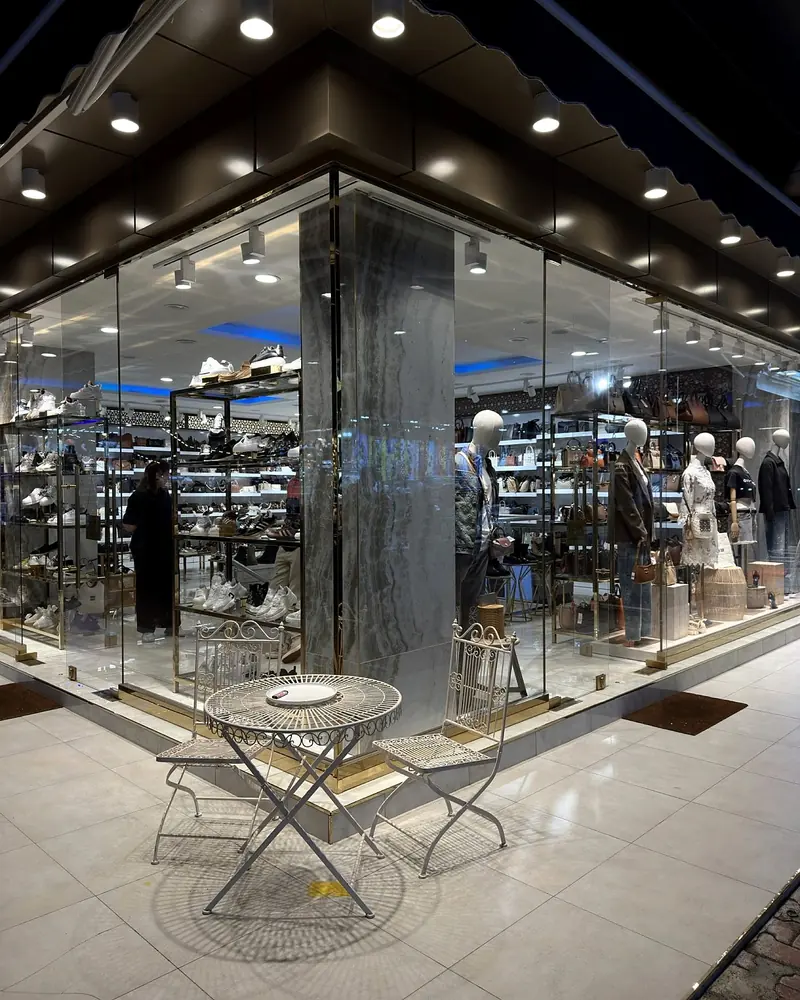 The glass corner storefront of BROTHERSBAG in Türkler, lit in the evening